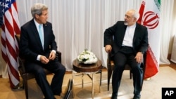FILE - U.S. Secretary of State John Kerry, left, waits with Iranian Foreign Minister Mohammad Javad Zarif before a meeting in Geneva, Switzerland, Jan. 14, 2015. 