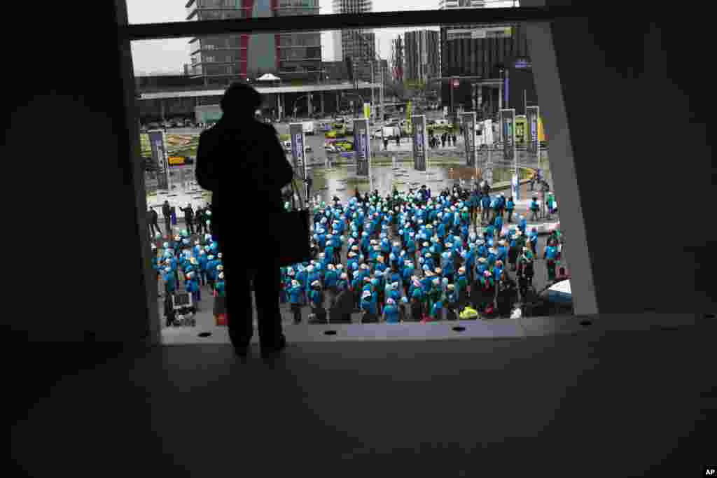 An attendee watches demonstrators from the Telefonica phone company protesting against what they claim are unjustified dismissals from the company, outside the Mobile World Congress, the world&#39;s largest mobile phone trade show, Barcelona, Spain.