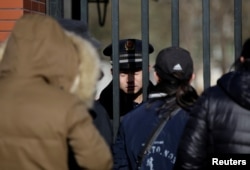 A security guard is pictured through the gate at the kindergarten run by pre-school operator RYB Education Inc being investigated by police, in Beijing, China, Nov. 24, 2017.