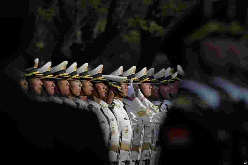 A Chinese People&#39;s Liberation Army soldier adjusts a hat of a member of an honor guard as they prepare a welcome ceremony for visiting Nigeria&#39;s President Muhammadu Buhari outside the Great Hall of the People in Beijing.