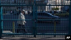 A man walks behind a locked passengers entrance of Athens' port of Piraeus which is on strike, May 6, 2016. 