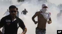 Anti-government protesters run away from tear-gas fired by riot police during a demonstration in Manama (file photo).