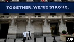 纽约证券交易所开市前，医护人员抵达时用手肘相互致意。在关闭了两个月之后，纽约证券交易所对交易员重新开放（2020年5月26日）。