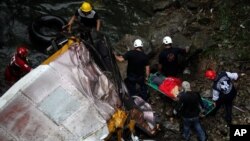 Rescue workers remove a body from a passenger bus that fell off the road into a ravine in Atoyac, Veracruz state, Mexico, Jan. 10, 2016.