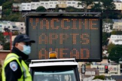 Seorang petugas berdiri di depan papan petunjuk pemberian vaksin di pusat vaksinasi drive-up di City College of San Francisco di San Francisco, 1 Februari 2021. (AP)