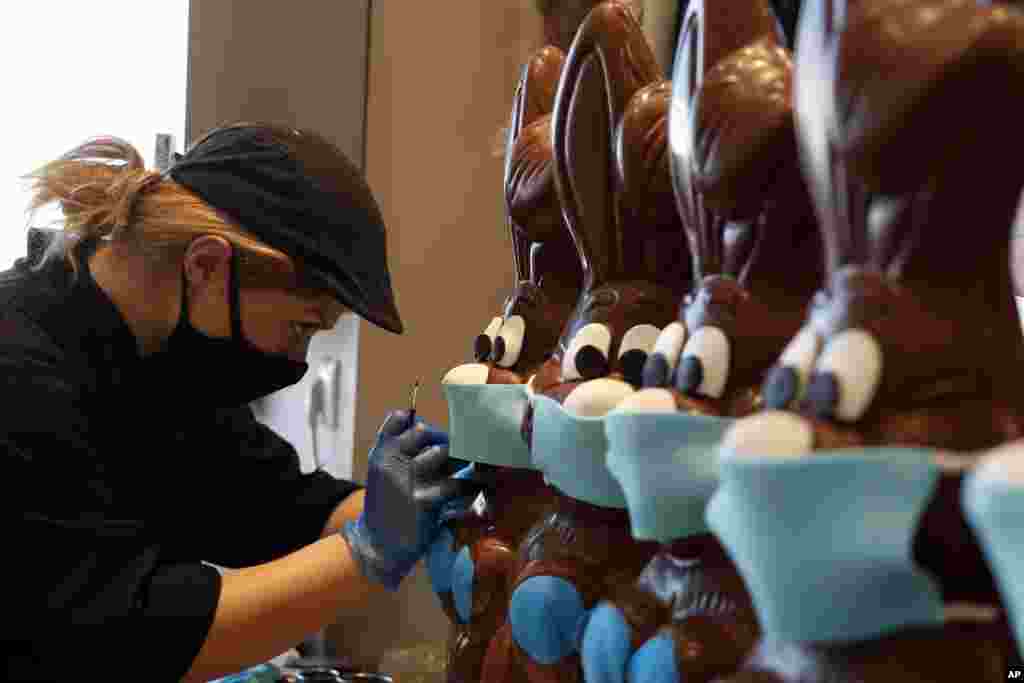 An employee of cake shop prepares chocolate Easter bunnies with masks in Lykovrisi, northern Athens, Greece.