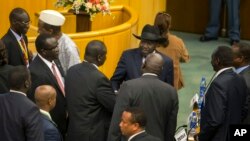 South Sudan's rebel leader Riek Machar, center-left with back to camera, shakes hands with South Sudan's President Salva Kiir, center-right wearing a black hat, after lengthy peace negotiations in Addis Ababa, Ethiopia, Aug. 17, 2015.
