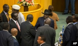 FILE - South Sudan's rebel leader Riek Machar, center-left, shakes hands with South Sudan's President Salva Kiir, center-right wearing a black hat, after lengthy peace negotiations in Addis Ababa, Ethiopia, Aug. 17, 2015.