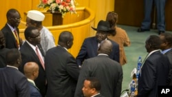 FILE - South Sudan's rebel leader Riek Machar, center-left with back to camera, shakes hands with South Sudan's President Salva Kiir, center-right wearing a black hat, after lengthy peace negotiations in Addis Ababa, Ethiopia, Aug. 17, 2015.
