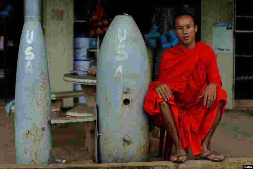 A Buddhist monk poses next to unexploded bombs dropped by U.S. Air Force planes during the Vietnam War, in Xieng Khouang, Laos.
