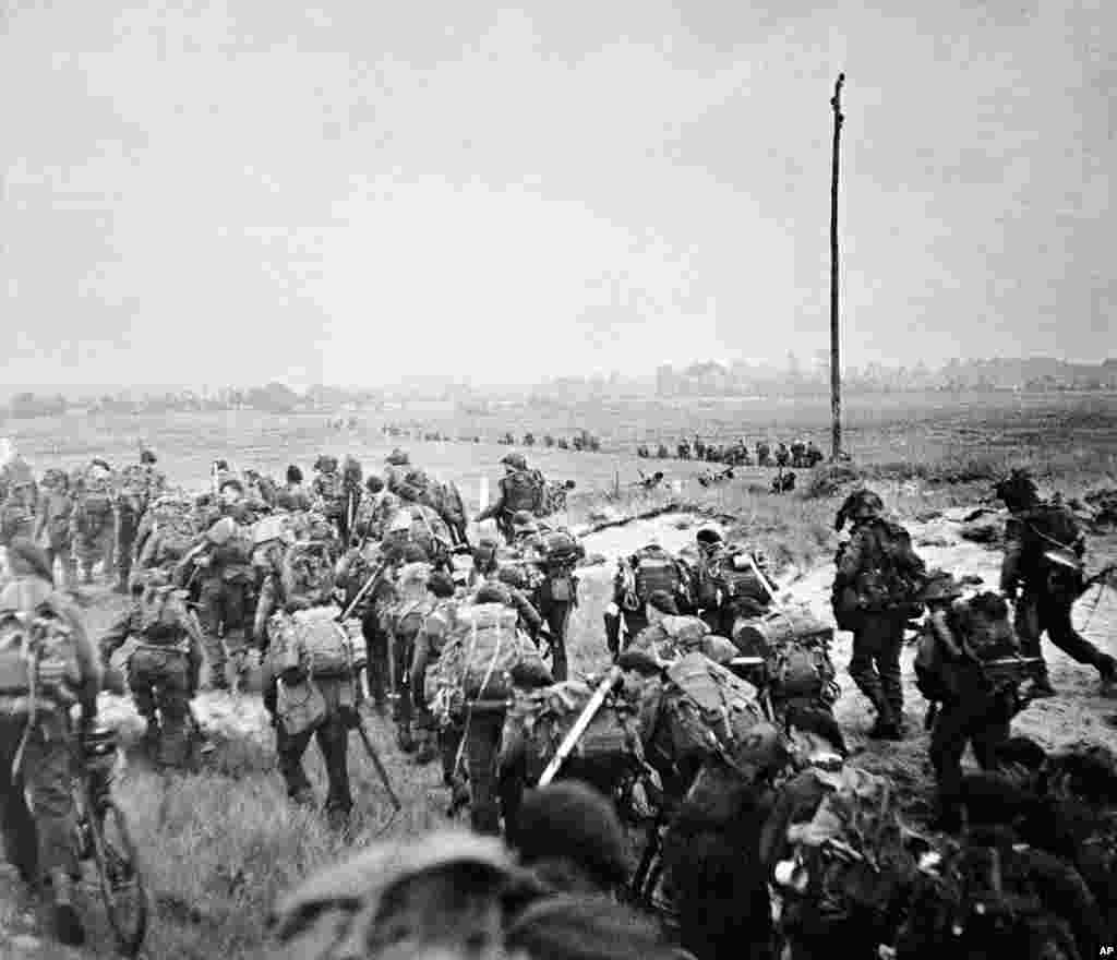 Special British commandos move inland from the beaches at Normandy under enemy shell, mortar and sniper fire, France, June 6, 1944.