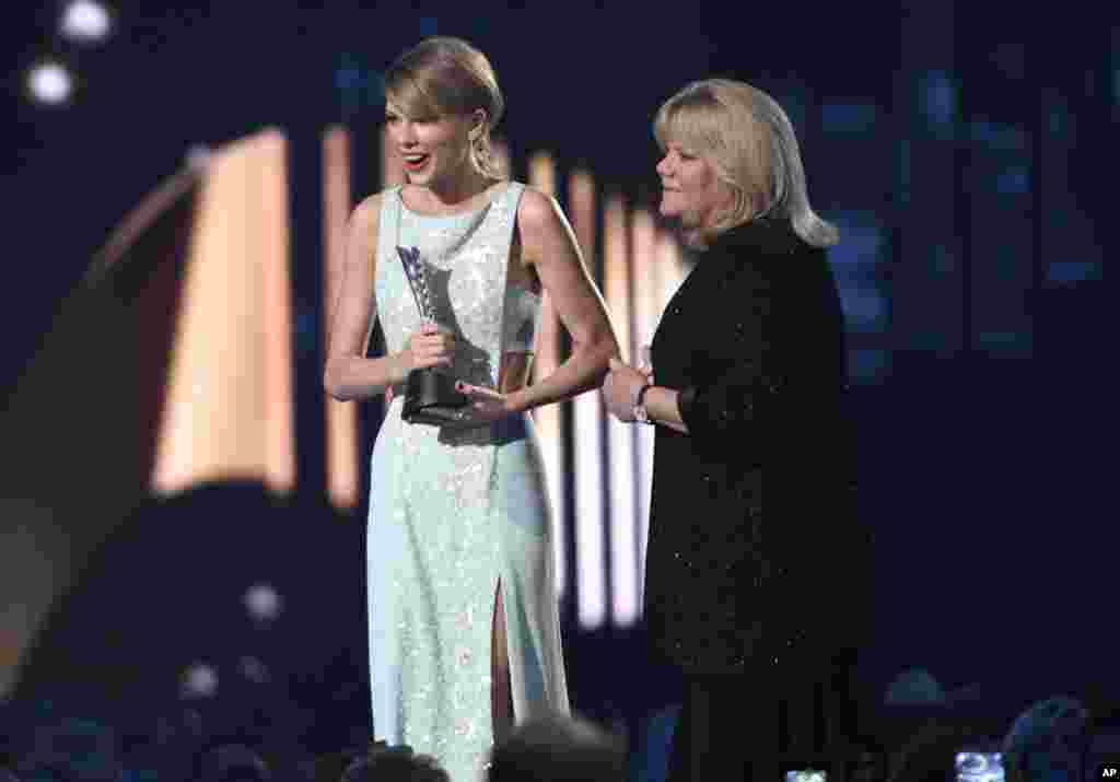 Andrea Finlay, right, presents the milestone award to Taylor Swift at the 50th annual Academy of Country Music Awards at AT&amp;T Stadium in Arlington, Texas, April 19, 2015.