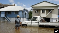 A man looks at a vehicle on a flooded street in the Brisbane suburb of Breakfast Creek, 12 Jan 2011