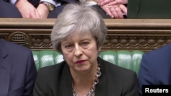 Britain's Prime Minister Theresa May listens as Jeremy Corbyn speaks in Parliament, London, Jan. 29, 2019.