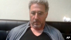 In this photo taken Sept. 3, 2017, a man identified by Italian Police as longtime fugitive Rocco Morabito looks down after being arrested in a Montevideo hotel, Uruguay. (Italian Police via AP)