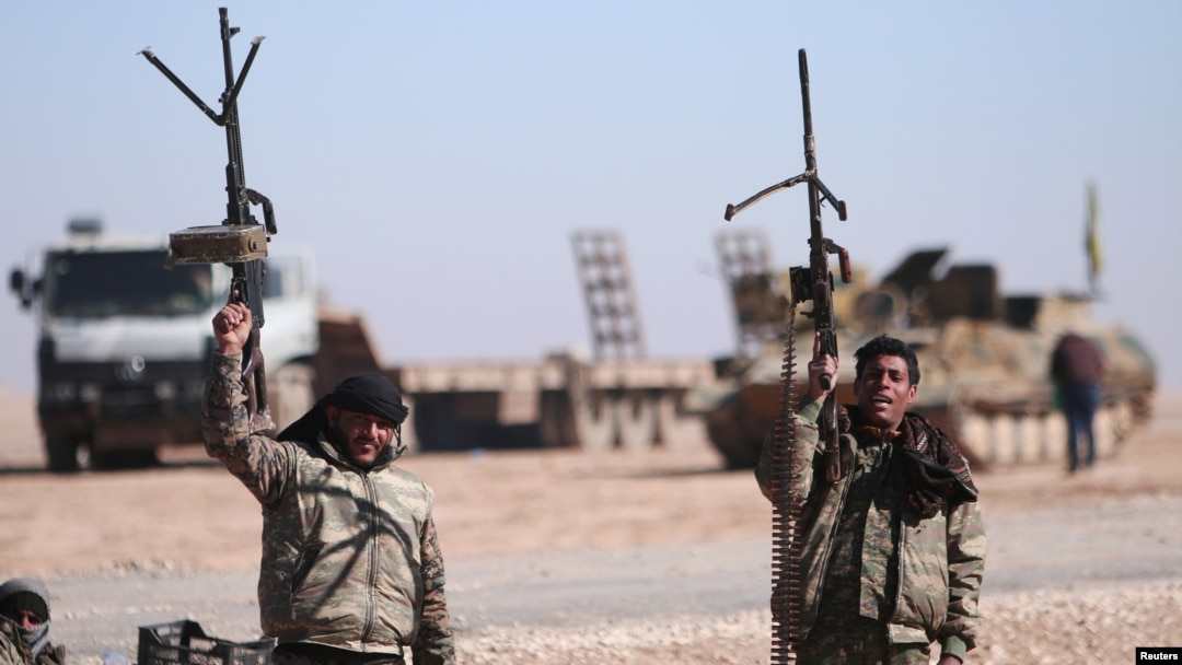 FILE - Syrian Democratic Forces fighters hold up their weapons in the north of Raqqa city, Syria, Feb. 3, 2017.