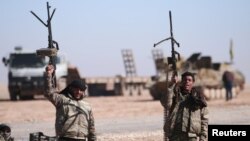 FILE - Syrian Democratic Forces fighters hold up their weapons in the north of Raqqa city, Syria, Feb. 3, 2017.