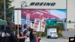 Boeing Machinists Union member Stephanie Corona waves to passing traffic while on the picket line at the Everett plant, Sept. 13, 2024, in Everett, Wash. 