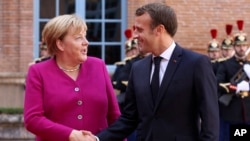 French President Emmanuel Macron welcomes German Chancellor Angela Merkel in the government building of Toulouse, southwestern France, Oct.16, 2019.