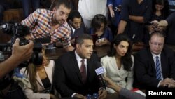 Al Jazeera television journalists Mohamed Fahmy, center, and Baher Mohamed, left, talk to the media with lawyer Amal Clooney, second from right, and Troy Lulashnyk, right, Canadian ambassador to Egypt, before hearing the verdict at a court in Cairo, Aug. 29, 2015.