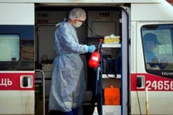 A medical worker wearing protective equipment sprays disinfectant at his ambulance after delivering a patient suspected of being infected with the coronavirus to the Pokrovskaya hospital in St.Petersburg, Russia, May 4, 2020.