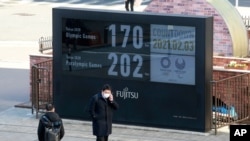 A man stands in front of a countdown clock for Tokyo Olympic and Paralympic Games in Tokyo, Wednesday, Feb. 3, 2021. Pressure is building on Japanese organizers and the IOC to explain exactly how they plan to hold the Tokyo Olympics in the midst of…