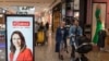 Shoppers walk past an electronic billboard showing a photo of New Zealand Prime Minister Jacinda Ardern in Christchurch, New Zealand, Wednesday, Oct. 14, 2020. Opinion polls indicate Ardern is on track to win a second term as prime minister in an…