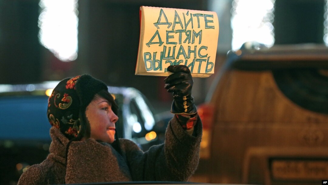 Seorang warga Moskow yang menentang UU adopsi baru di Rusia memegang poster bertuliskan "Beri anak kesempatan hidup." (AP/Mikhail Metzel)