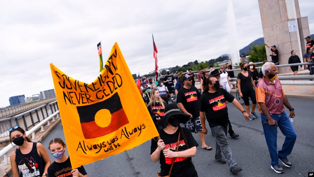 Para pengunjuk rasa memegang plakat saat berpawai dalam aksi protes menandai peringatan 50 tahun Kedutaan Besar Aborigin, di Canberra, Rabu, 26 Januari 2022. (Lukas Coch/AAP Image via AP)