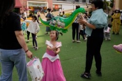 A child holds a dinosaur balloon on Children's Day at a mall in Beijing on June 1, 2021.