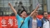 A student pose for a photo after taking the 2014 college entrance exam of China, or the "gaokao", outside a high school in Beijing, June 8, 2014.