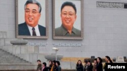 1일 평양 김일성 광장에 걸려있는 김일성.김정일 초상화 앞을 지나는 북한 주민들.