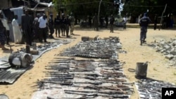 Wani dan sanda yana duba gine gine da ababan hawa da kuma makamai bayan harin da kungiyar Boko Haram ta kai a Damaturu ranar 25 da 25 ga watan Oktoba. An dauki hotunan ranar 28 ga watan Oktoba, 2013.