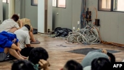 Alleged scam center workers and victims sit next to dismantled IT and electronic appliances during a crackdown operation by the Karen Border Guard Force (BGF) on illicit activity in Shwe Kokko in Myanmar's eastern Myawaddy township on Feb. 18, 2025.