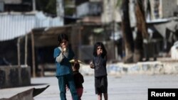 FILE - Children eat corn on the cob on a street in Douma, eastern al-Ghouta, near Damascus.