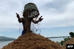 FILE - Odilon Salima empties a basket filled with sand, that was collected from the Ubangi river, on the banks of the river in Bangui on November 8, 2023.