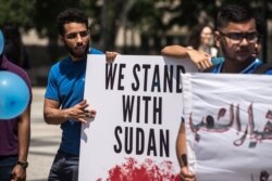 Protesters hold signs at a rally in support of the Sudan's revolution, in Chicago, Illinois, June 29, 2019. (J. Patinkin/VOA)