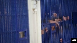 在曼谷市中心的警察移民拘留中心，被拘留者站在牢房栅栏后面。人权组织于2023年4月27日敦促泰国改善其移民拘留设施的条件，因为在两个月内又有一名来自中国的维吾尔族寻求庇护者在拘留期间死亡。（资料照片：2019年1月21日）