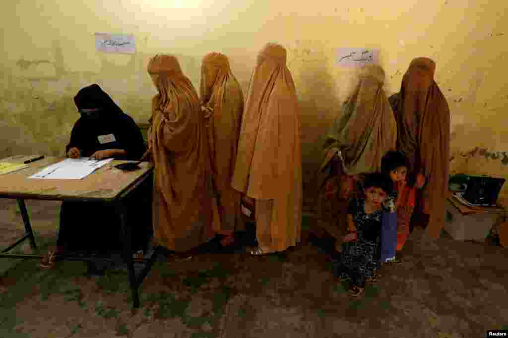 Women, clad in burqas, stand in line to cast their ballot at a polling station during general election in Peshawar, Pakistan.