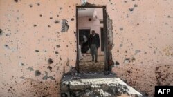 FILE - People walk inside their damaged house in the Sur district in Diyarbakir, Turkey, Dec. 11, 2015.