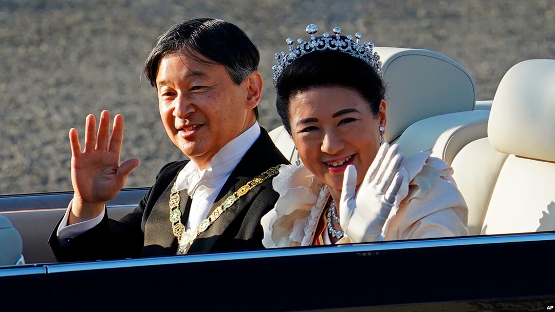 Kaisar Naruhito dan Ratu Masako melambai kepada warga yang menunggunya di sepanjang jalan di Tokyo hari Minggu (10/11). 