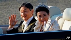 Kaisar Jepang Naruhito, kiri, dan Permaisuri Masako, kanan, melambaikan tangan selama iring-iringan kerajaan di Tokyo, Minggu, 10 November 2019. (AP Photo/Eugene Hoshik)