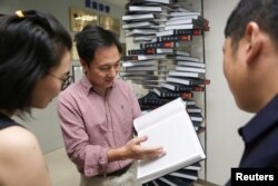 FILE - Scientist He Jiankui shows "The Human Genome", a book he edited, at his company Direct Genomics in Shenzhen, Guangdong province, China, Aug. 4, 2016.