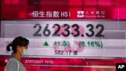 Una mujer pasa junto a la pizarra electrónica de un banco que muestra el índice de acciones de Hong Kong en la Bolsa de Valores de Hong Kong en Hong Kong el martes 27 de julio de 2021.