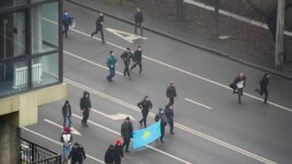 Demonstrators with Kazakhstan's national flag march during a protest in Almaty, Kazakhstan, Wednesday, Jan. 5, 2022. (AP Photo/Vladimir Tretyakov)