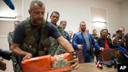 A pro-Russian fighter places a black box from the crashed Malaysia Airlines Flight 17 on a table while handing it over from Donetsk People's Republic officials to Malaysian representatives in the city of Donetsk, eastern Ukraine, July 22, 2014. Senior Ukrainian separatist leader Aleksander Boroda, (wearing a blue jacket) stands off to the right.