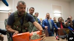 یک شورشی حامی روسیه در شرق اوکراین جعبه سیاه هواپیمای مالزی را در مراسم تحویل آن به مقامات مالزی روی میز می گذارد.