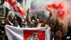 People light flares and wave Belarusian flags to support Belarusian opposition in front of Belarusian Embassy in Kyiv, Ukraine, Aug. 14, 2020. 