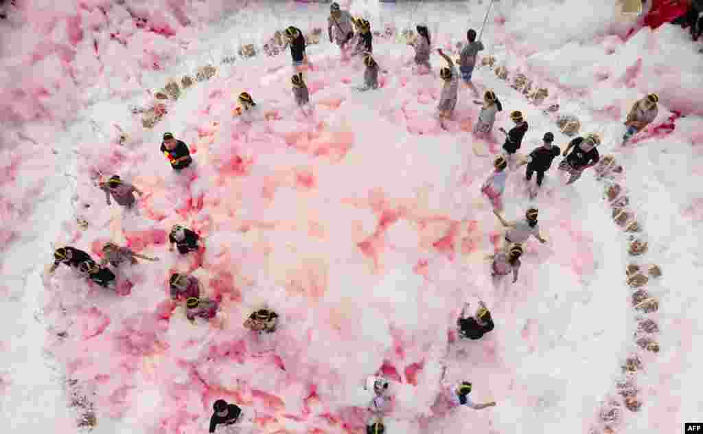 People play in a foam substance mixed with chili pepper water in Ningxiang county, in China&#39;s central Hunan province, July 2, 2019.