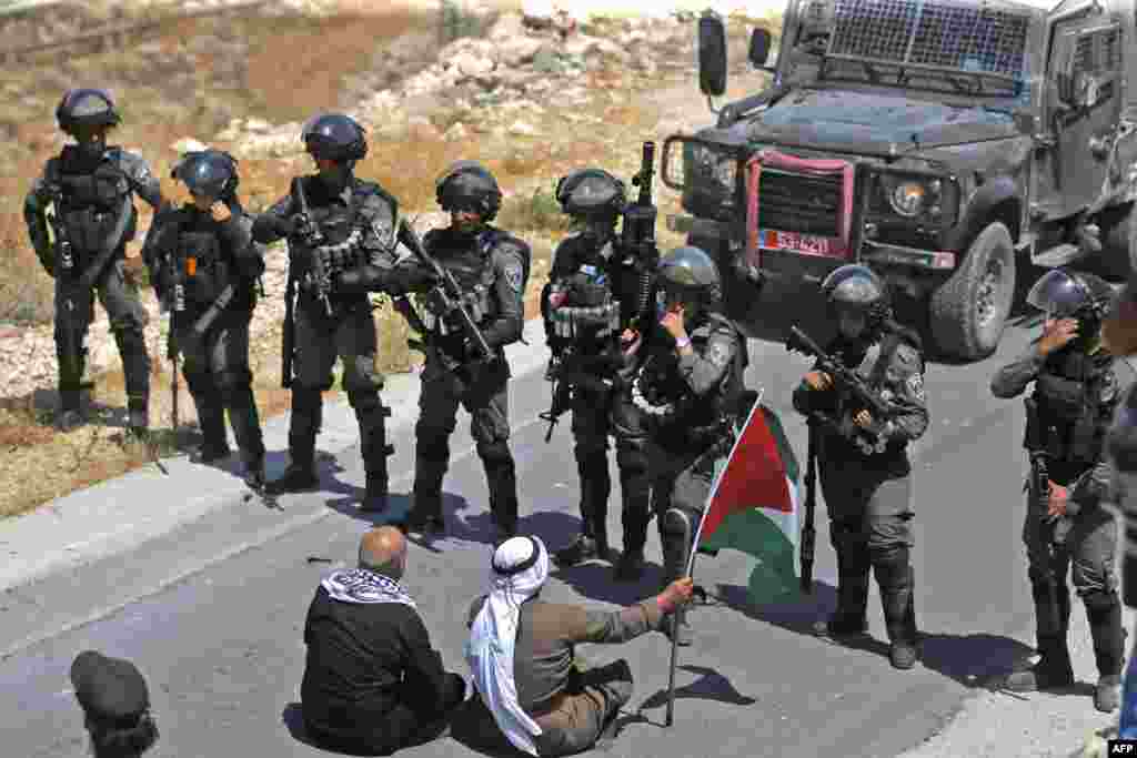 Palestinian protesters sit before Israeli troops during a demonstration against the seizing of Palestinian land by Israel, in the village of Kafr Malik northeast of Ramallah in the Israeli-occupied West Bank.